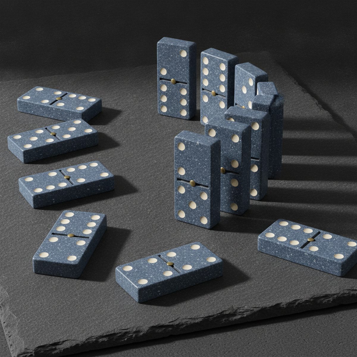 Speckled slate-blue dominoes with ivory pips, standing and scattered mid-game on dark slate.